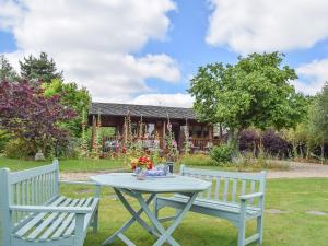 a table and two benches in a yard with a house at Lakeside Cabin in Kingston Blount