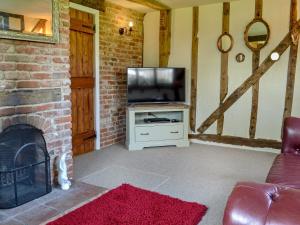 uma sala de estar com televisão e lareira em The Old Stables em Rickinghall