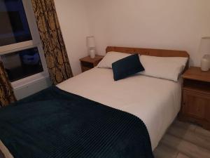 a bedroom with a white bed with a blue pillow on it at Ardara Town centre 2 Bed Apt in Donegal