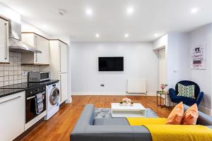 a living room with a couch and a kitchen at Bright St Johns Apartments in London
