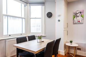 a dining room with a table and chairs and a clock at Bright St Johns Apartments in London