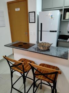 een keuken met 2 stoelen en een aanrecht met een koelkast bij Reserva em Ubatuba Homme Resort in Ubatuba