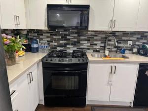 a kitchen with a black stove and a microwave at one bedroom basement apartment in Milton