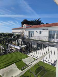 a balcony of a building with lawn chairs and a building at Hôtel Le Martray in Ars-en-Ré