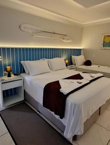 una habitación de hotel con una cama grande con sábanas blancas en NAVEGA PRAIA HOTEL, en Navegantes