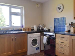 a kitchen with a washing machine and a sink at Cherrytree Cottage in Loftus
