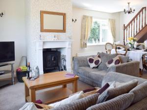 a living room with a couch and a fireplace at Cherrytree Cottage in Loftus
