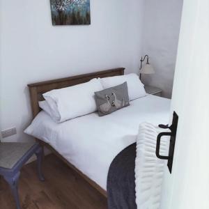 um quarto com uma cama branca e uma cadeira em Ballymultimber Cottages em Limavady
