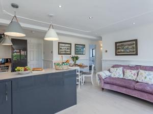 a kitchen and a living room with a purple couch at Buttercup Cottage in Halsall