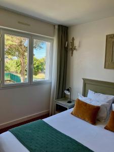 a hotel room with a bed and a window at Hôtel Le Martray in Ars-en-Ré
