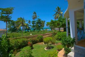 a house with a garden with palm trees and the ocean at B&B Aparthotel La Isleta in Las Galeras