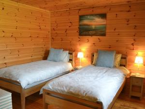 Duas camas num quarto com paredes de madeira em Wiki Wheels em Saint Columb Major