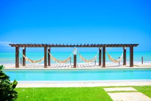 a swimming pool with a hammock and the ocean at Waterfront Apart Hotel in Maceió