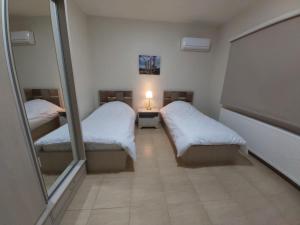 um pequeno quarto com 2 camas e um espelho em CMK Housing em Madaba