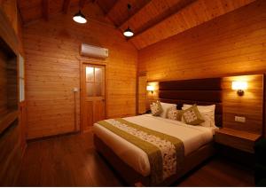 a bedroom with a bed in a wooden cabin at Antaraal Resort & Spa A Village Resort in Dharamshala