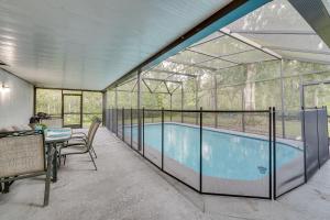 - une piscine dans une maison en verre avec une table et des chaises dans l'établissement Spacious Kissimmee Family Home with Pool and Patio!, à Kissimmee