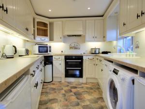 een keuken met witte kasten en een wasmachine en droger bij Irenic Lodge 2 in Netley