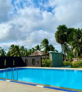 a swimming pool in front of a house with palm trees at Joe's Beach Shack - Beach resort, Ramanathapuram in Mandapam
