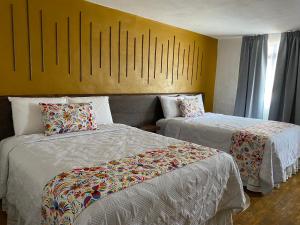 Habitación de hotel con 2 camas y pared amarilla en PASEO REAL HOTEL BOUTIQUE, en Uruapan del Progreso