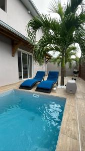 een zwembad met blauwe ligstoelen en een palmboom bij Bel'Vie in Le François