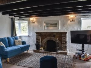 a living room with a blue couch and a fireplace at Pollards Cottage in Forrabury