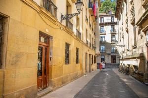 two people walking down an alley in a city at Old Town Homestay in San Sebastián