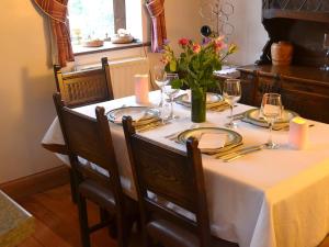 a table with a white table cloth and a vase of flowers at Willow Down in Downham