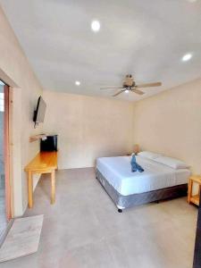a bedroom with a bed and a desk and a ceiling fan at Tiki Bantayan Cebu Tourist Inn Inc in Pooc