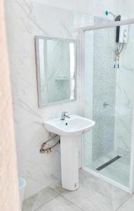 Baño blanco con lavabo y espejo en Tiki Bantayan Cebu Tourist Inn Inc en Pooc