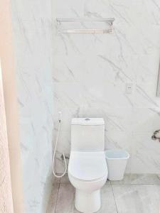 La salle de bains blanche est pourvue de toilettes et d'un tuyau. dans l'établissement Tiki Bantayan Cebu Tourist Inn Inc, à Pooc