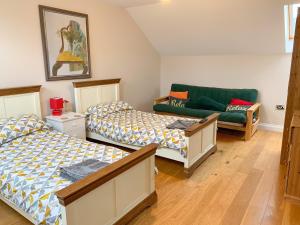 a bedroom with two beds and a green couch at Harrowbeard House in Marhamchurch