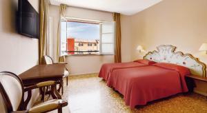 1 dormitorio con 2 camas, escritorio y ventana en Residenza dei Fiori, en Cannero Riviera