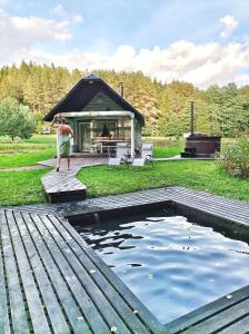 une femme debout devant un bassin d'eau dans l'établissement White homestead, à Semeliškės