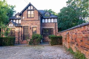 una vieja casa de ladrillo con una pared de ladrillo en Detached house with gated parking in Whalley Range en Mánchester