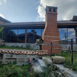 een huis met een stenen schoorsteen en een gebouw bij Guest Rooms Didka in Koprivshtitsa