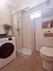 a bathroom with a shower and a toilet and a washing machine at Detached house with gated parking in Whalley Range in Manchester