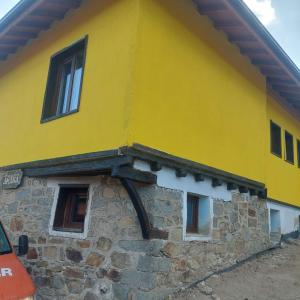 um edifício amarelo com janelas do lado em Guest Rooms Didka em Koprivshtitsa