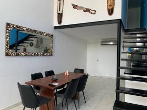 une salle à manger avec une table en bois et des chaises noires dans l'établissement Fancy Loft near 5th av and beach, à Playa del Carmen