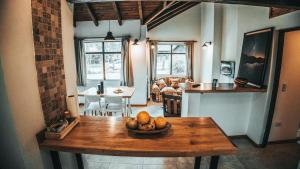cocina y sala de estar con mesa y un bol de fruta en Sombra Verde en Villa La Angostura