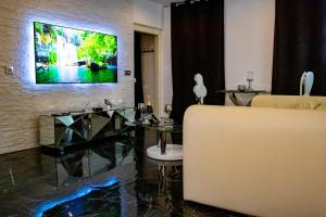 a living room with a couch and a television on a wall at La Duchesse 1976 - Love Room Spa in Vernon