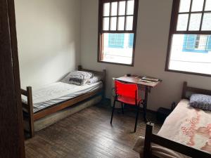 a bedroom with a bed and a desk with a red chair at Republica Do Arco Da Velha in Ouro Preto