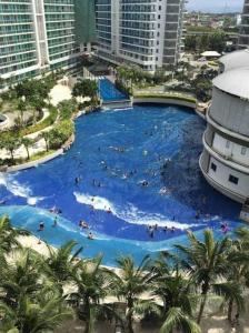 a large swimming pool in a city with people in it at Manila Urban Resort at Azure in Manila