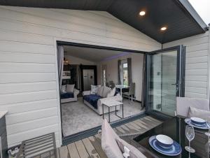 a patio with a couch and a table on a deck at Waterside Lodge - Dog Friendly Sutton on Sea in Sutton on Sea