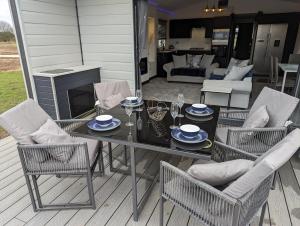 a patio with a table and chairs and a living room at Waterside Lodge - Dog Friendly Sutton on Sea in Sutton on Sea