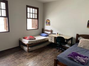 a room with two beds and a desk in it at Republica Do Arco Da Velha in Ouro Preto