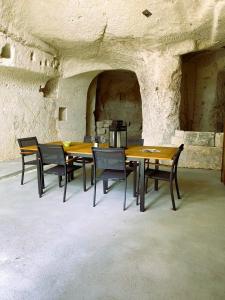 a group of wooden tables and chairs in a stone room at La troglo aux oiseaux in Montrichard