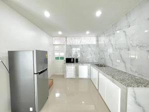 a kitchen with a stainless steel refrigerator and white cabinets at Sealife4 Beach Pool Villa in Rayong