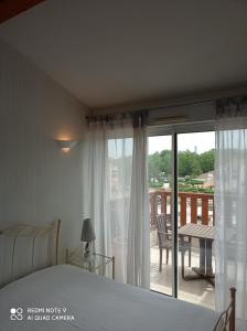 um quarto com uma cama e vista para uma varanda em Ombre et soleil vue sur la lagune et bateaux em Saint-Cyprien