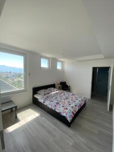een slaapkamer met een bed en een groot raam bij Charmant appartement près de EPFL UNIL Lausanne in Renens