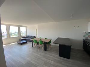 een woonkamer met een tafel en groene stoelen bij Charmant appartement près de EPFL UNIL Lausanne in Renens